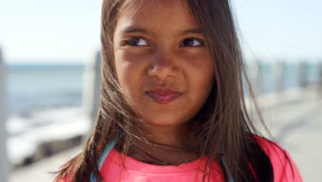 child, face and wind in hair on a beach promenade