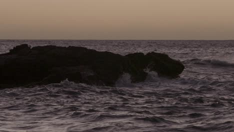 Waves-crashing-into-large-rock-in-the-Pacific-ocean-during-sunset