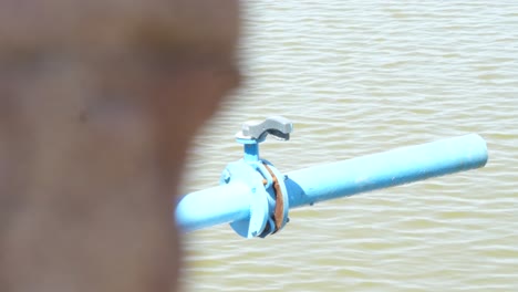 dolly right reveal of blue water pipe with outflow pipe beside body of water