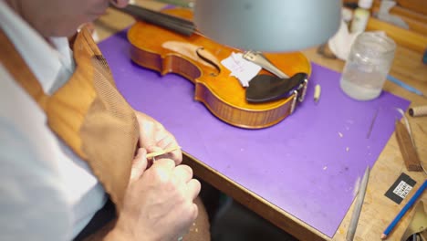 anonymous luthier with violin bridge in workshop