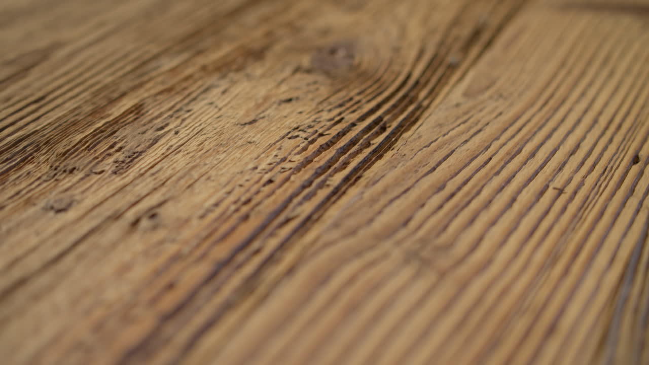 High quality video showing close up wooden surface with rich grain warm light and subtle texture captured in slow motion for a natural detailed and calm atmosphere