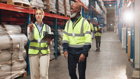 two warehouse workers discuss inventory and logistics in a large warehouse