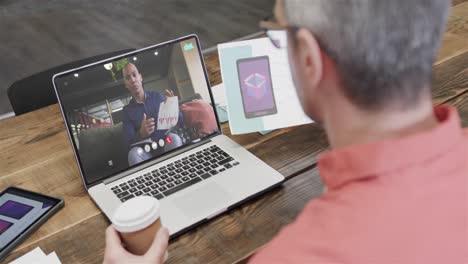 Caucasian-businessman-on-laptop-video-call-with-african-american-male-colleague-on-screen