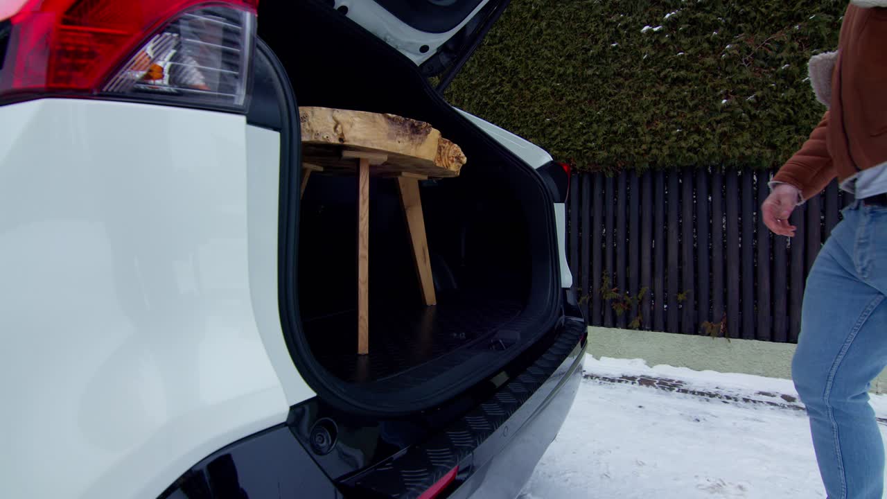 오프로드 자동차 트렁크에 작은 나무 탁자를 놓는 청년에게 확대