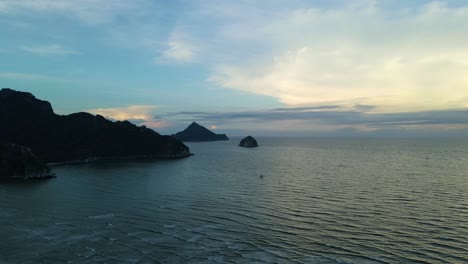 Hermoso-Cielo-De-Puesta-De-Sol-En-Tonos-Azules-Que-Revelan-El-Océano,-La-Isla-Y-Las-Montañas-En-Silueta