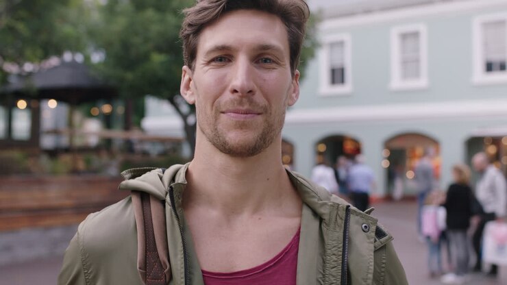 ritratto di un bel giovane che sorride allegro davanti alla telecamera sullo sfondo urbano