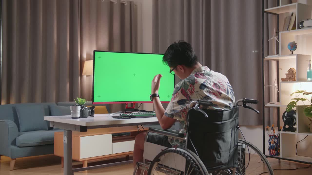 체어 에 앉아 있는 사람 이 녹색 화면 을 가진 컴퓨터 에서 일 하고 있다