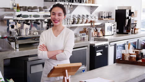 Young-female-coffee-shop-owner-behind-counter,-crossing-arms