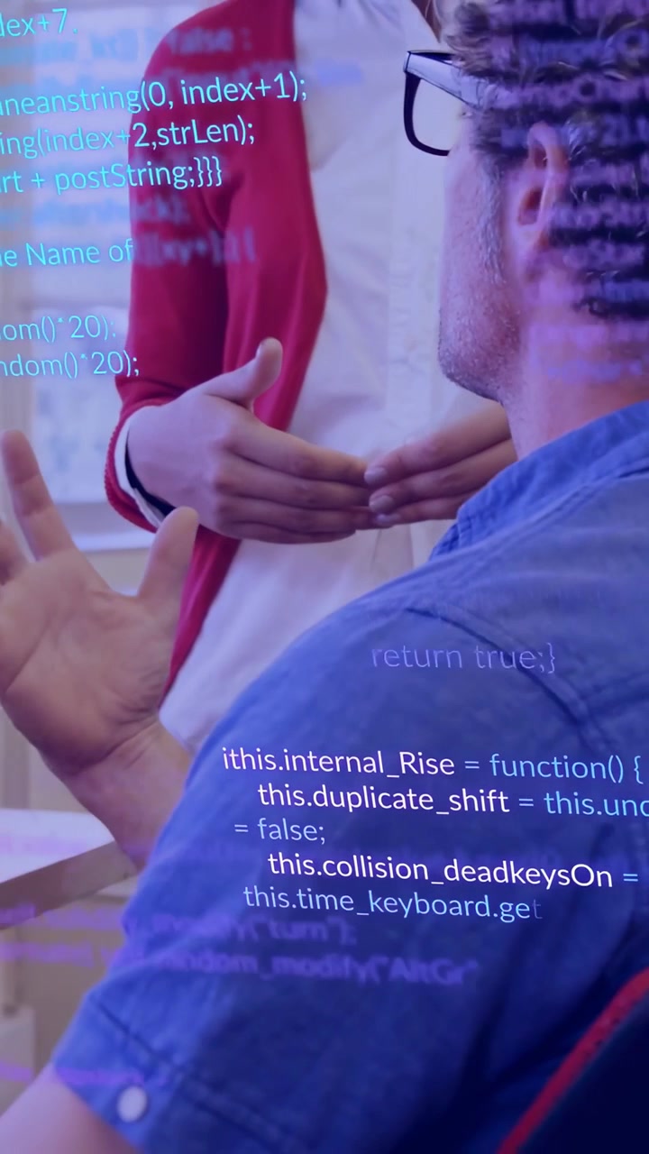 Vertical video: Seated man gesturing while woman pointing and leaning, reviewing code with overlay