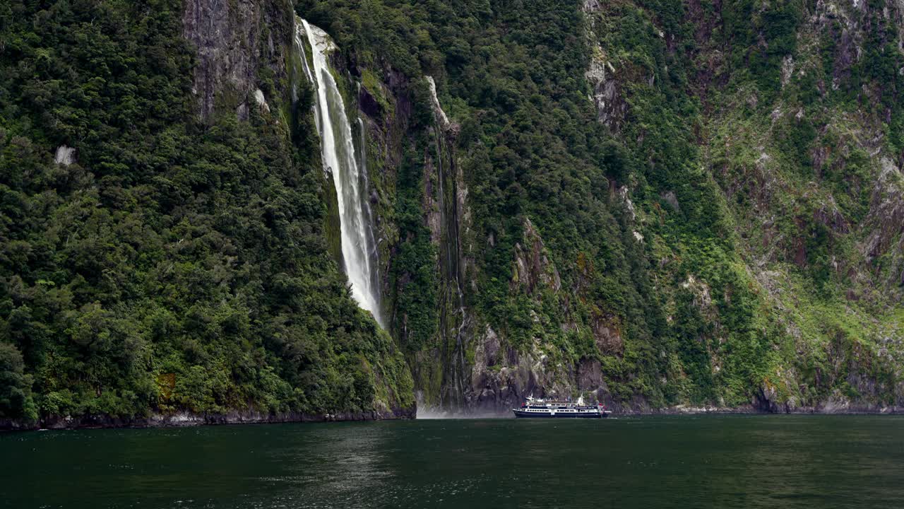 밀포드 사운드 (milford sound) 로 흘러 들어가는 웅장한 폭포는 울창한 나무가 있는 바위 절벽에서 아져 나옵니다.