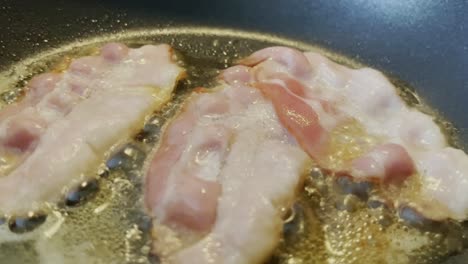 Delicious-thin-ham-frying-in-a-black-pan-with-lots-of-fat