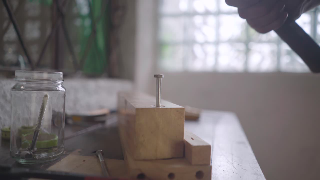 Close-up of a man's hand hammering a nail into wood board 4K