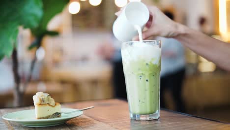 Milch-In-Einen-Eisgekühlten-Shake-Gießen,-Während-In-Einer-Cafeteria-Ein-Stück-Kuchen-Auf-Dem-Tisch-Steht