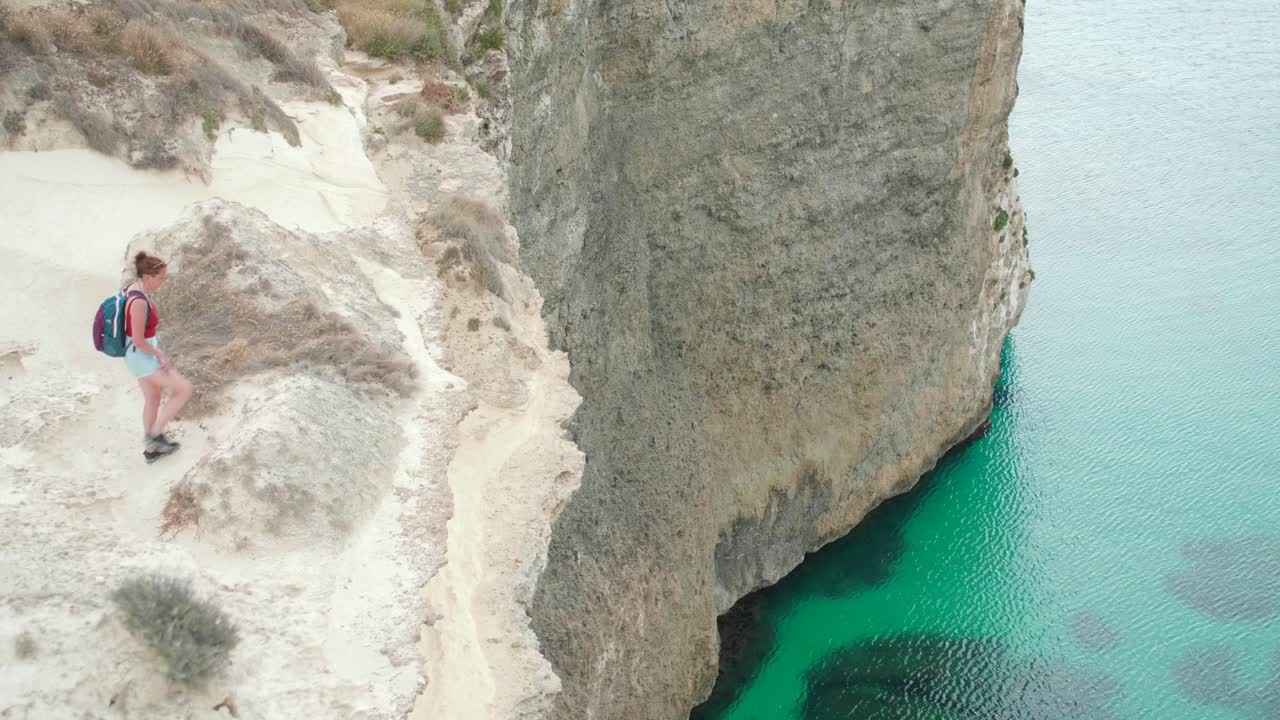 excursionista femenina en la cima de un acantilado sobre el mar mediterráneo, costa de malta, paisaje escénico en el día de verano, vista amplia