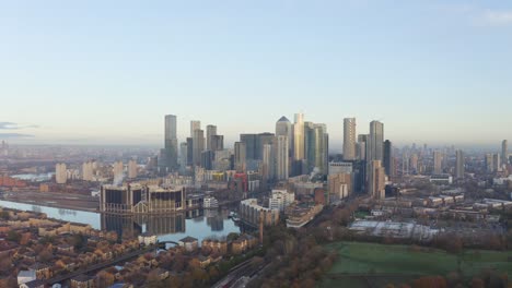 cinematic circling right drone shot of canary wharf skyscrapers from the south at sunrise