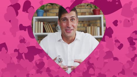 animación de un marco en forma de corazón sobre un hombre caucásico proponiendo con un anillo en una videollamada portátil