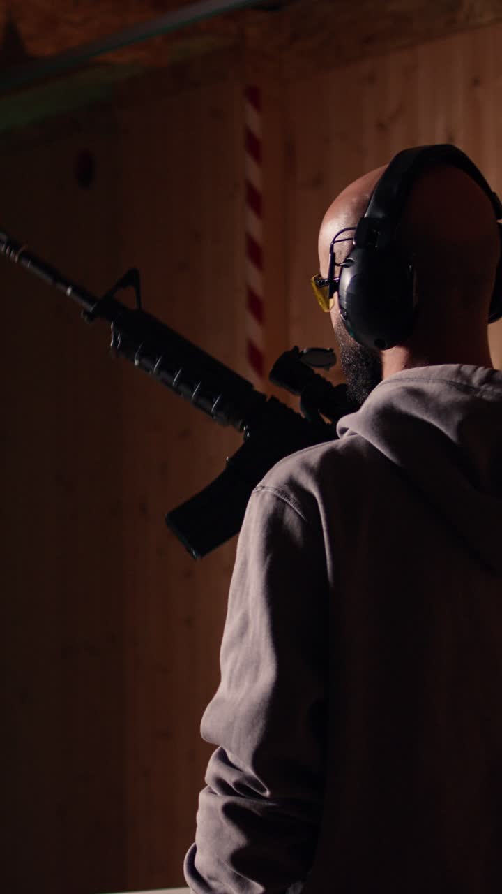 Vertical video Shooting gallery client using rifle to hit targets, wearing protection headset