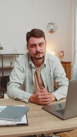 upset unhappy man guy showing thumbs down sign gesture expressing discontent sitting at table