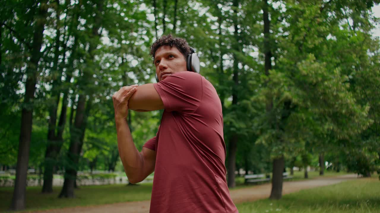 Uomo che fa stretching con le cuffie nel parco