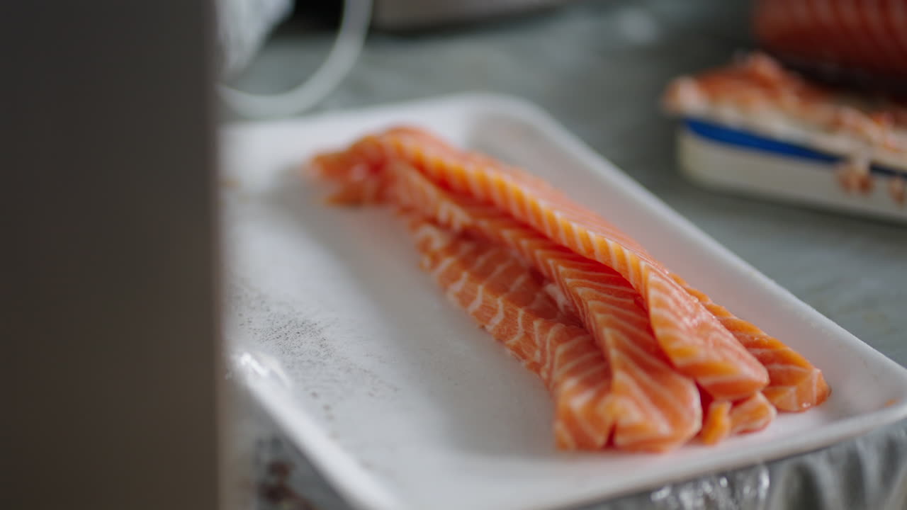 Pan shot of fresh salmon on a white tray in a kitchen, indoor, slow motion
