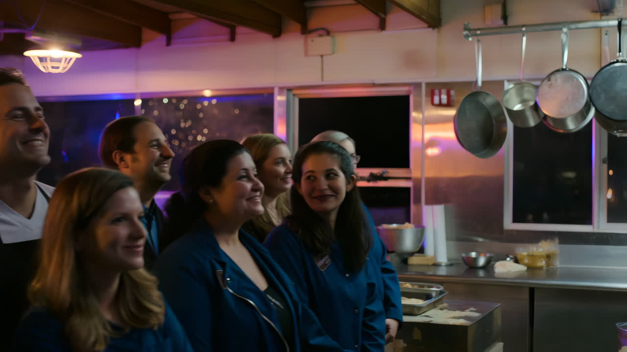 A group of smiling people gathered in a professional kitchen setting