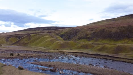 aerial drone shot flying over a shallow stream towards a hillside in the north yorkshire moors