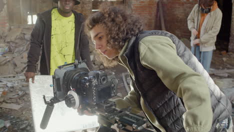 close up view of cameraman setting up a camera in a ruined building while anothers coworkers wating for start the recording