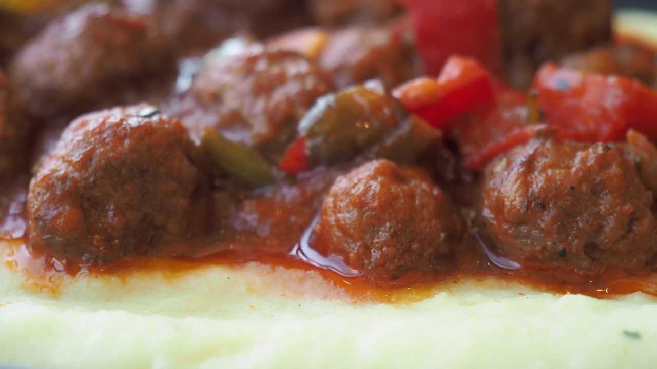 cerca de un plato de albóndigas con puré de patatas y salsa roja