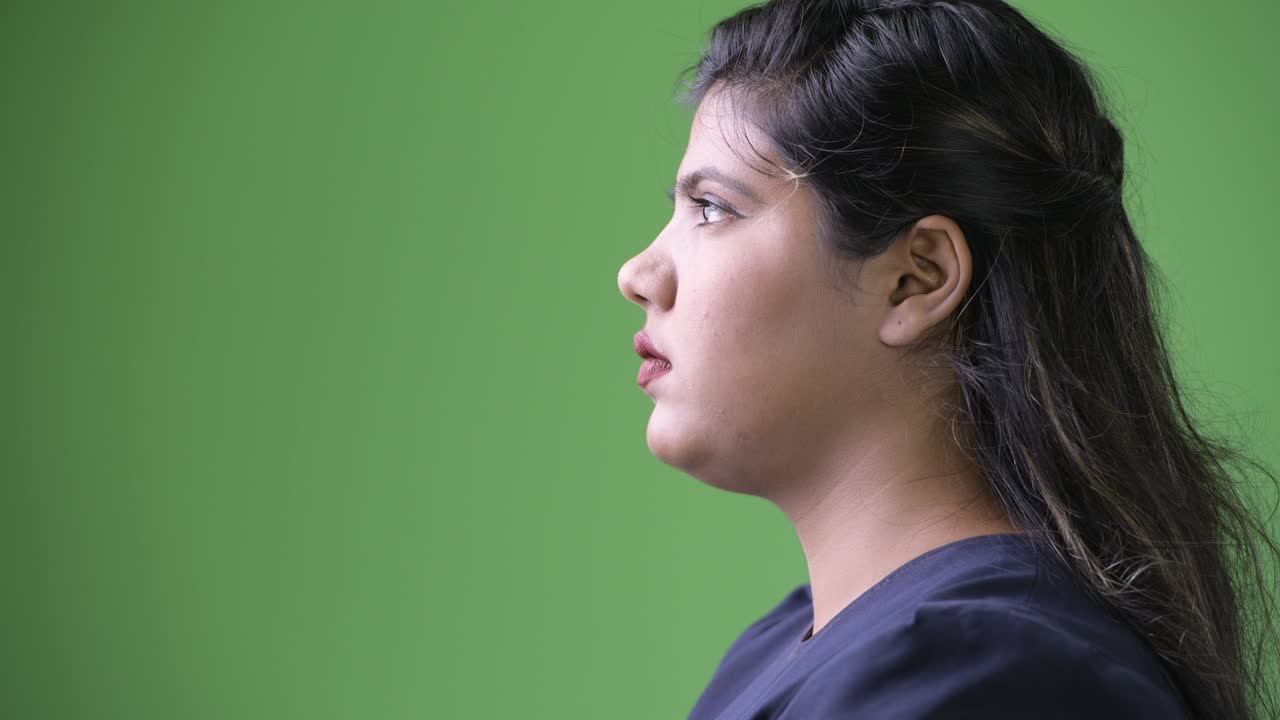 Young overweight beautiful Indian businesswoman against green background