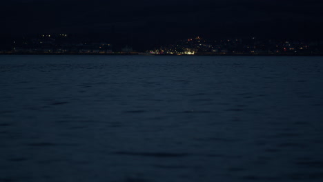 low angle telephoto compressed view of coastal town lights on at night