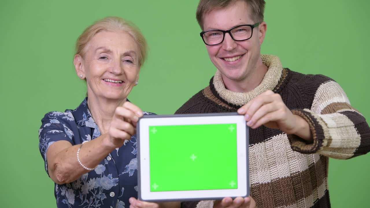 Happy grandmother and grandson showing digital tablet together