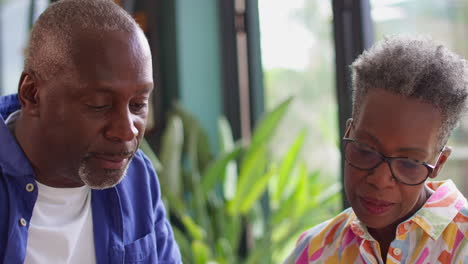 Senior-Couple-Sitting-Around-Table-At-Home-Having-Serious-Discussion-Reviewing-Finances