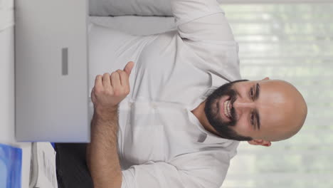 vertical video of home office worker man rejoices at what he sees on the laptop.