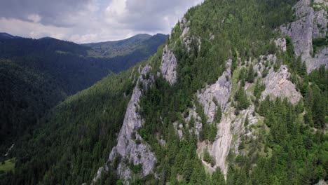 drone flying in between giant rocks revealing forest mountain landscape