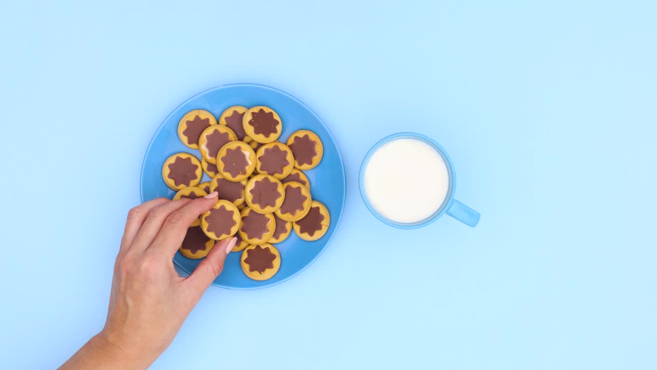 Blue plate filling with cookies and blue cup filling with milk. Stop motion