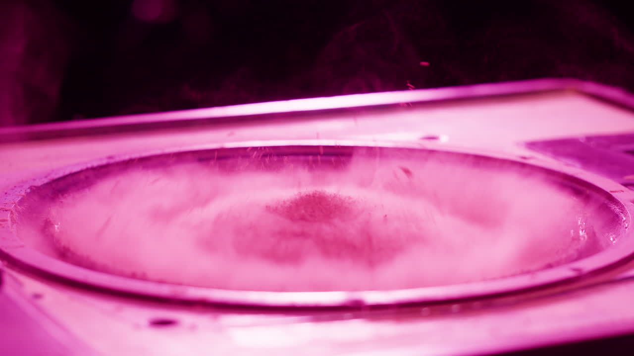 Polvere rosa che danza su un cono vibrante di un altoparlante