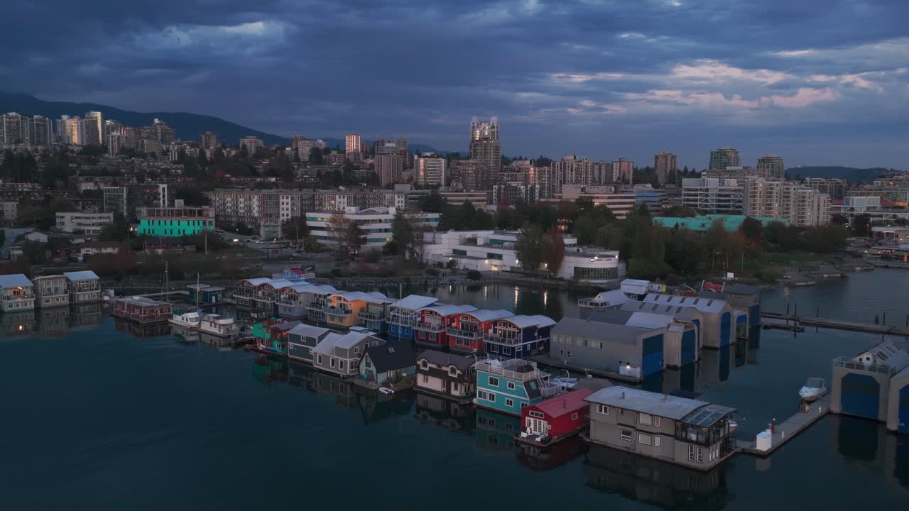 Aerial wide descending shot of floating homes and houseboats on the North Vancouver shore at twilight in British Columbia, Canada. 4K