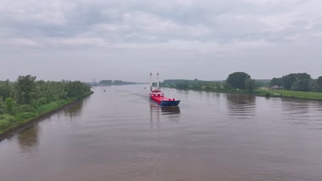 a cargo ship navigates a river or canal under a cloudy sky