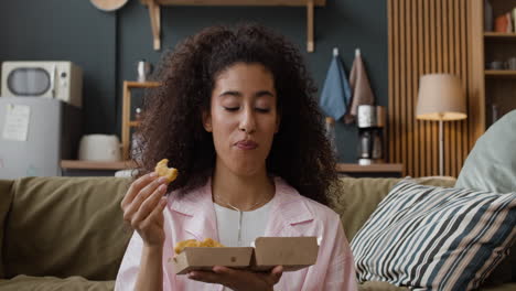woman enjoying fast food snack on couch at home