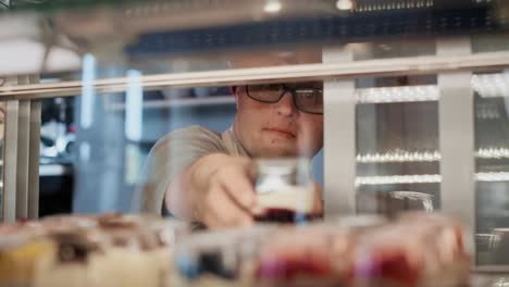 Caucasian-man-with-down-syndrome-taking-a-dessert-from-the-fridge-to-serve-in-a-cafe.