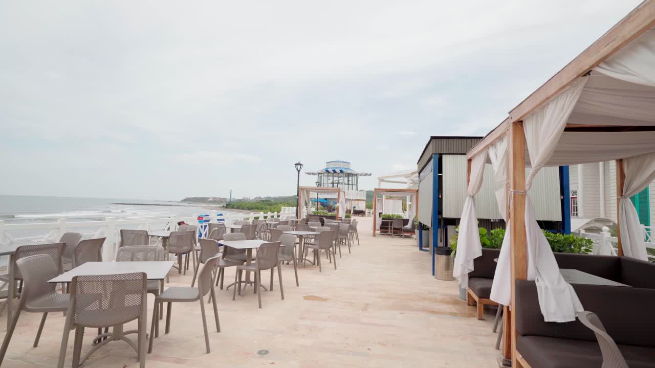 Empty tables and chairs at a seaside cafe terrace on a cloudy day overlooking the ocean, colombia