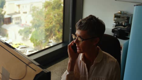 Businesswoman-talking-on-mobile-phone-at-desk-4k