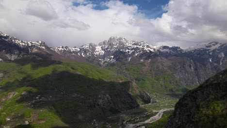 el pueblo aparece después de un bosque verde en las altas montañas de los alpes albaneses