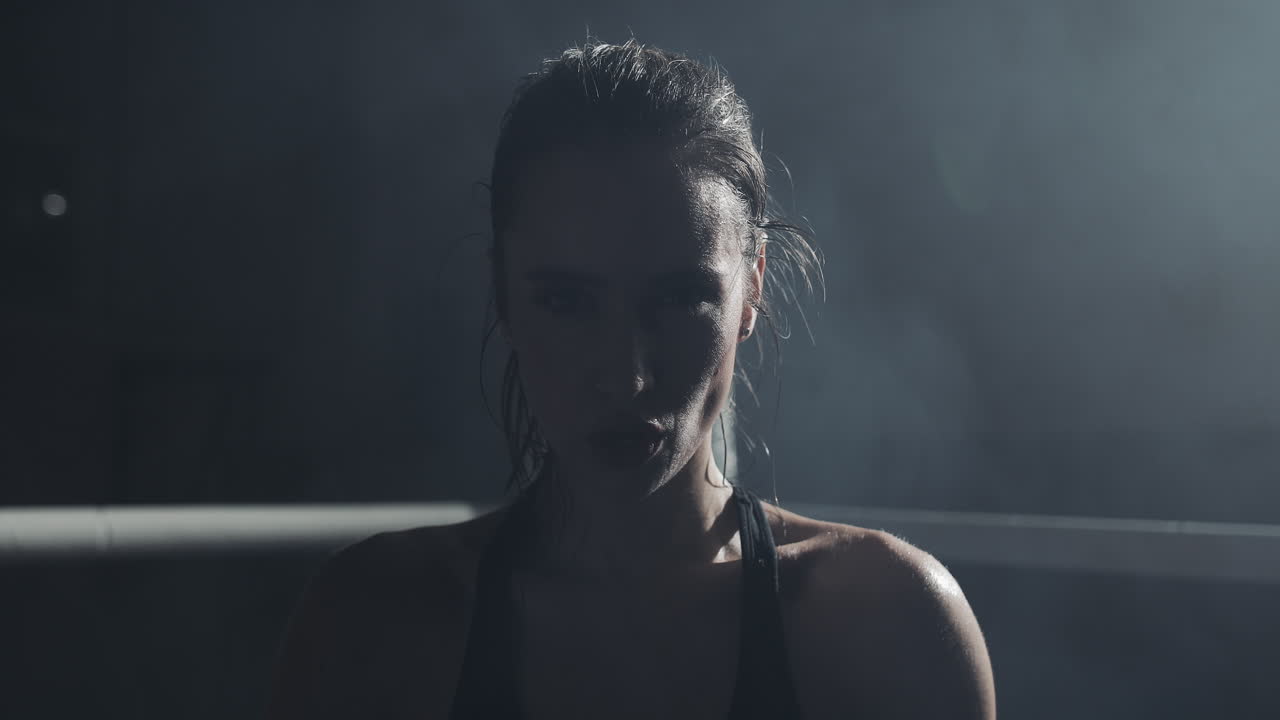 Intense Portrait of a Sweaty Female Athlete in a Dark Setting