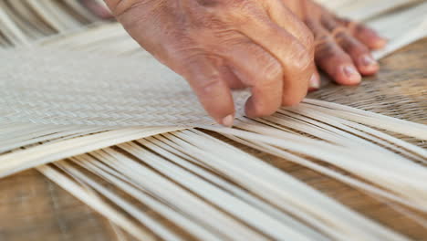 bamboo weaving, slow-motion closeup of carefully aligning bamboo strips with fingernails, elderly woman hand waving bamboo with her hands