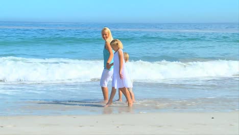 woman and her daughters walking on a beach