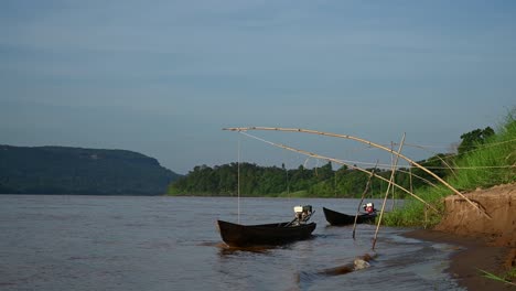 botes largos con motores amarrados rebotando con las olas del río mekong, ya que es un cuerpo de agua que fluye rápidamente