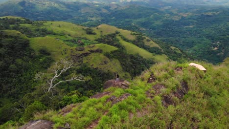 mujer de pie sola en la cima de una pequeña montaña en haputale, sri lanka, después de caminar hasta la cima