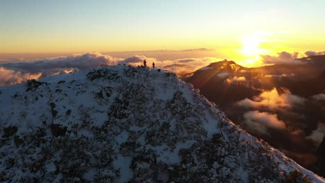 two people standing at the top during a bright sunset