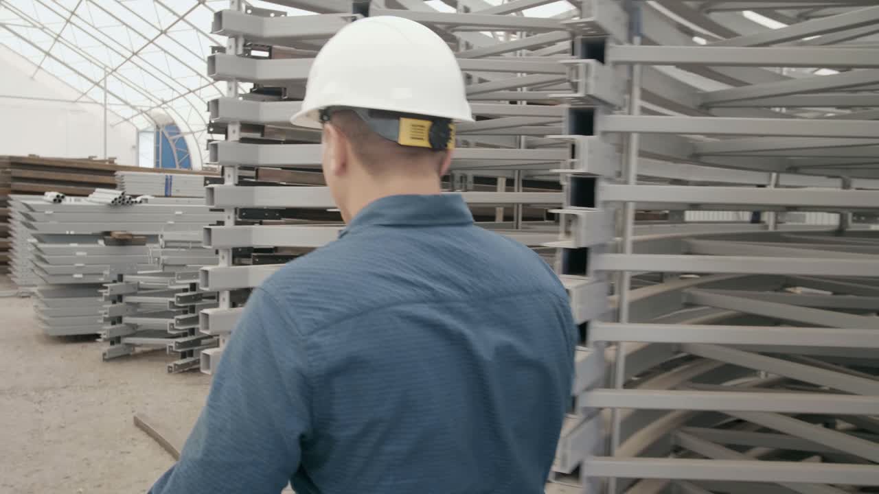Worker Inspecting Metal Beams in Warehouse